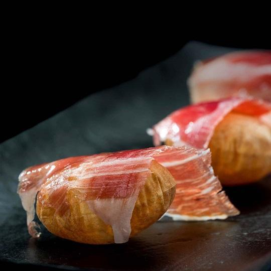 Fein geschnittener Iberico-Schinken, auf traditionelle Weise präsentiert in Form eines köstlichen Tapas.